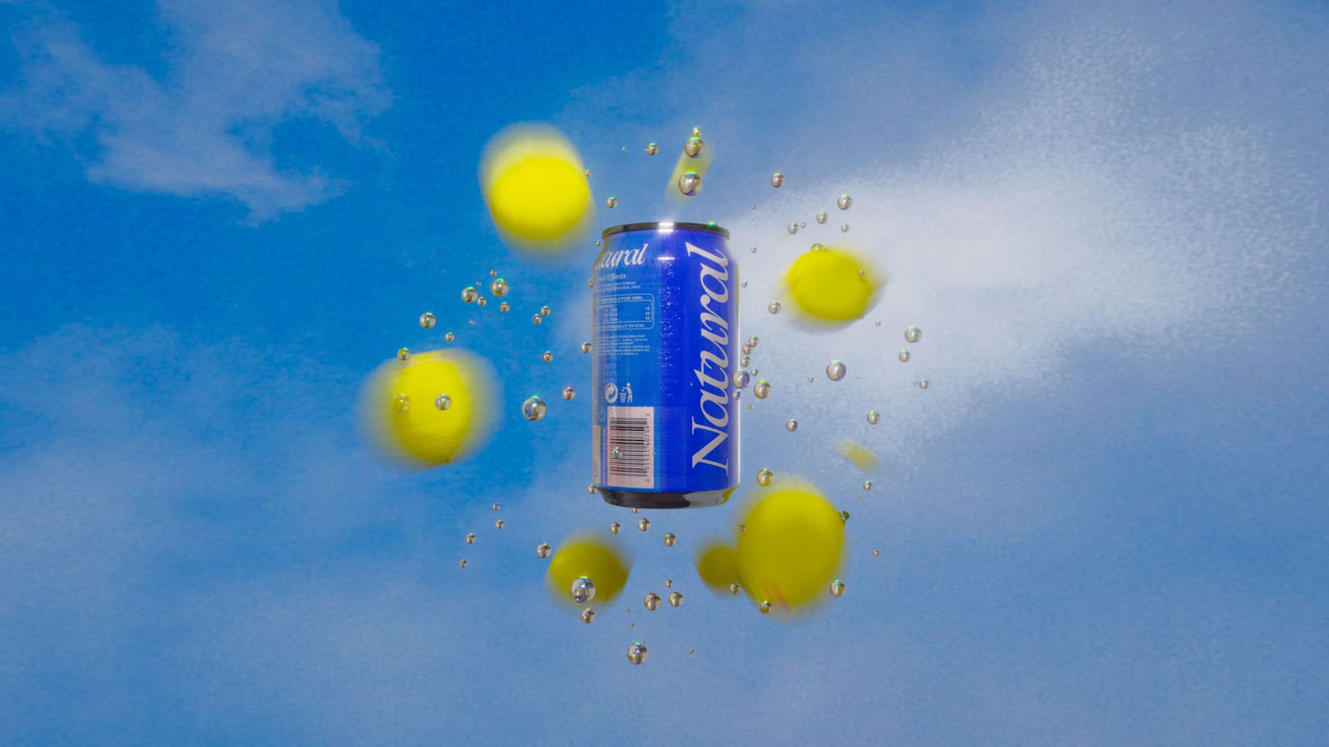 Blue “Natural” can floating in the sky among blurred yellow spheres and bubbles